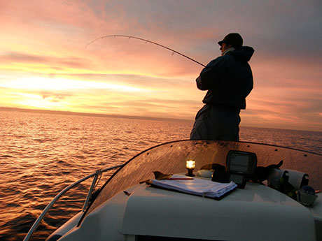 Pescador recreativo pescando calamar de potera al amanecer